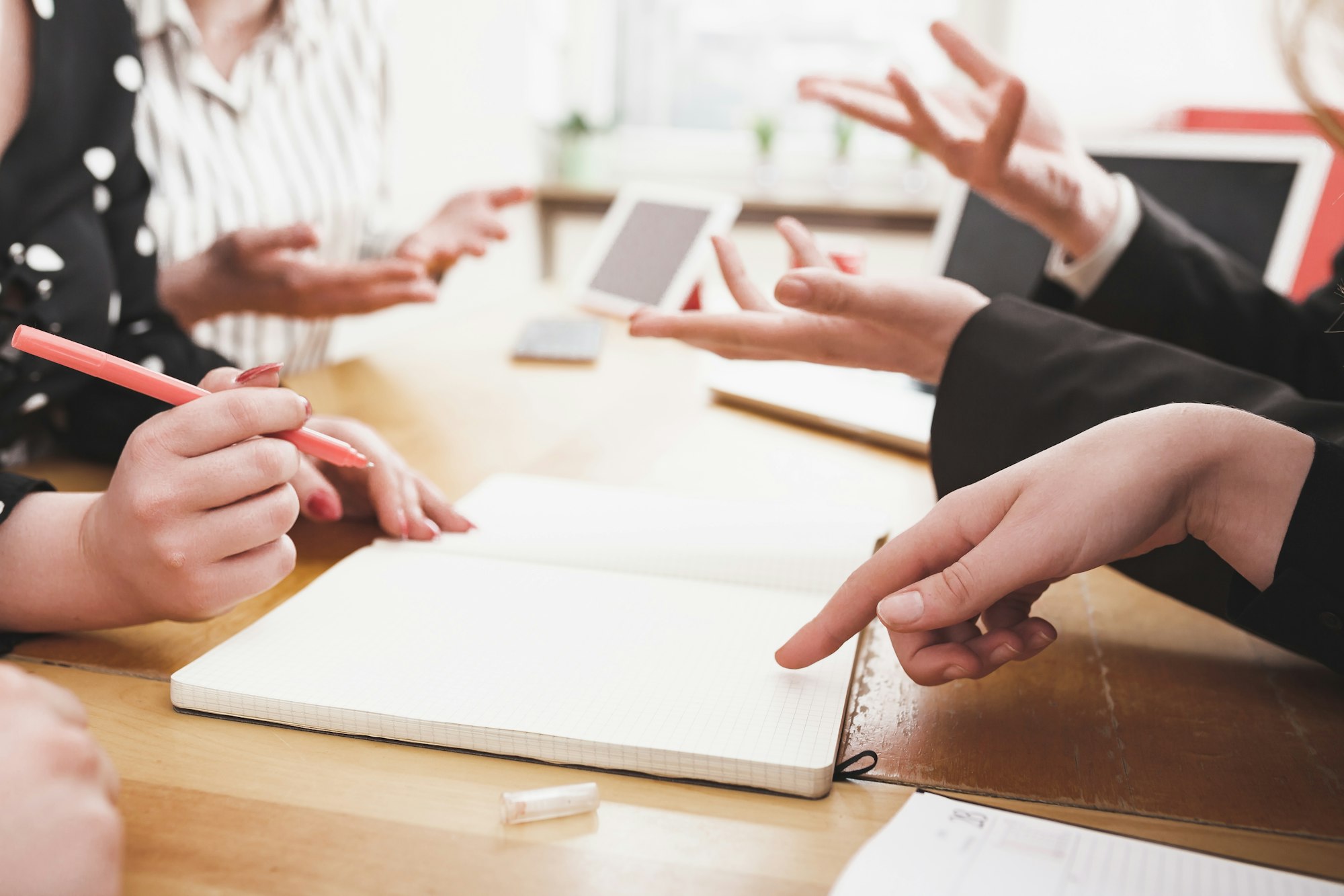 Young business team working together, discussing and writing on small office desk